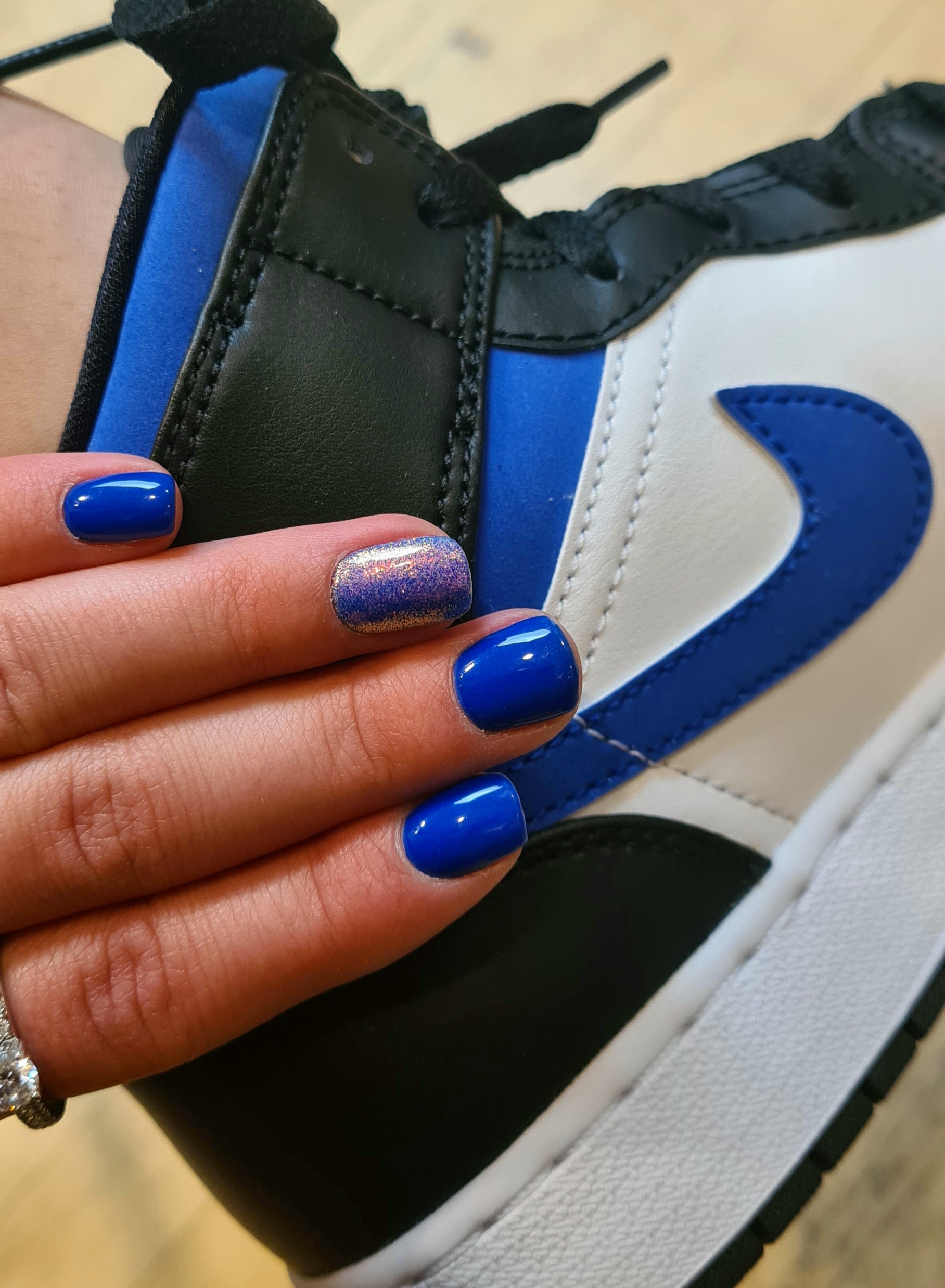 Kobaltblauwe nagels naast een sneaker