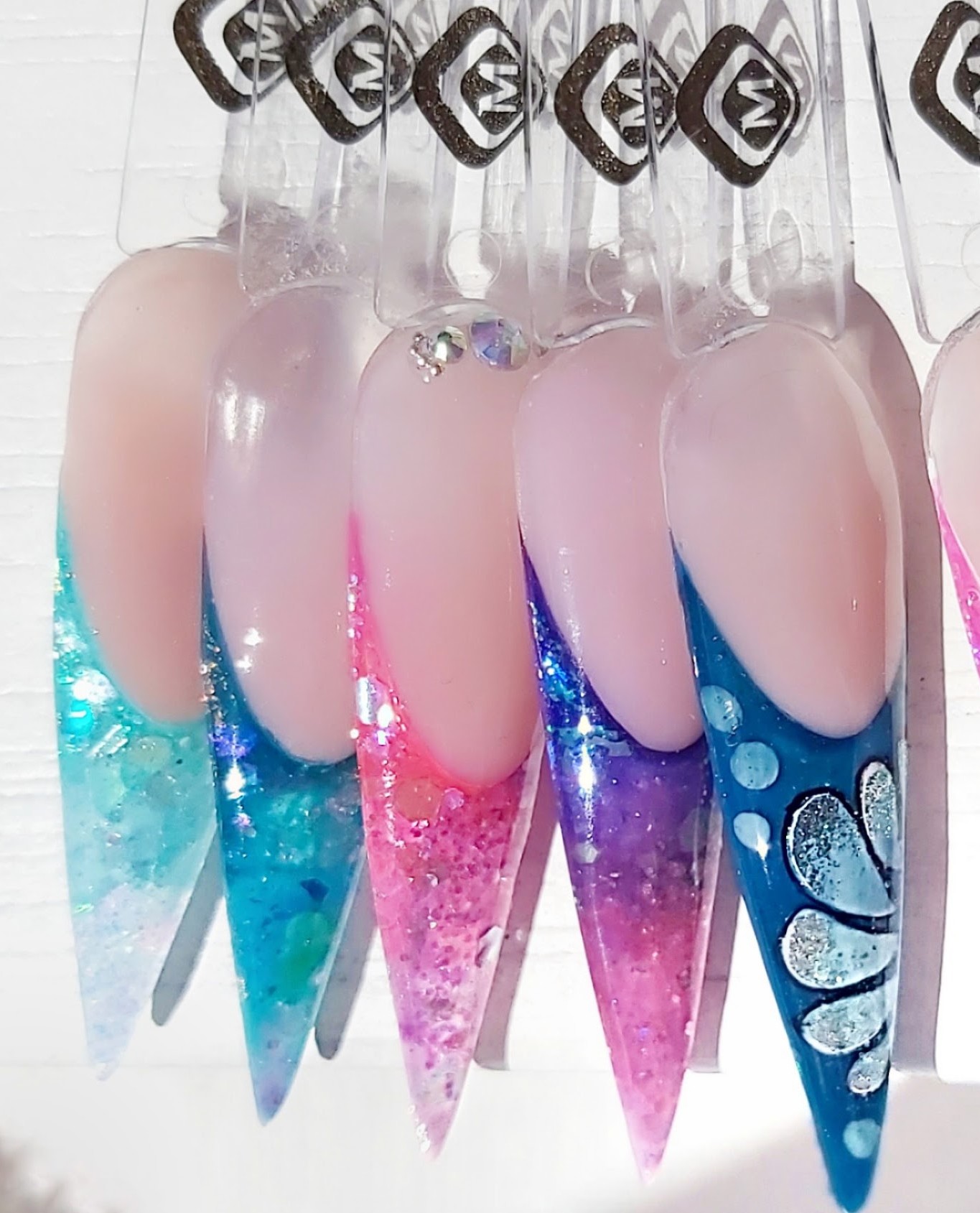 Stiletto-tips in French en ombré met glitter, op een rij displaystokjes